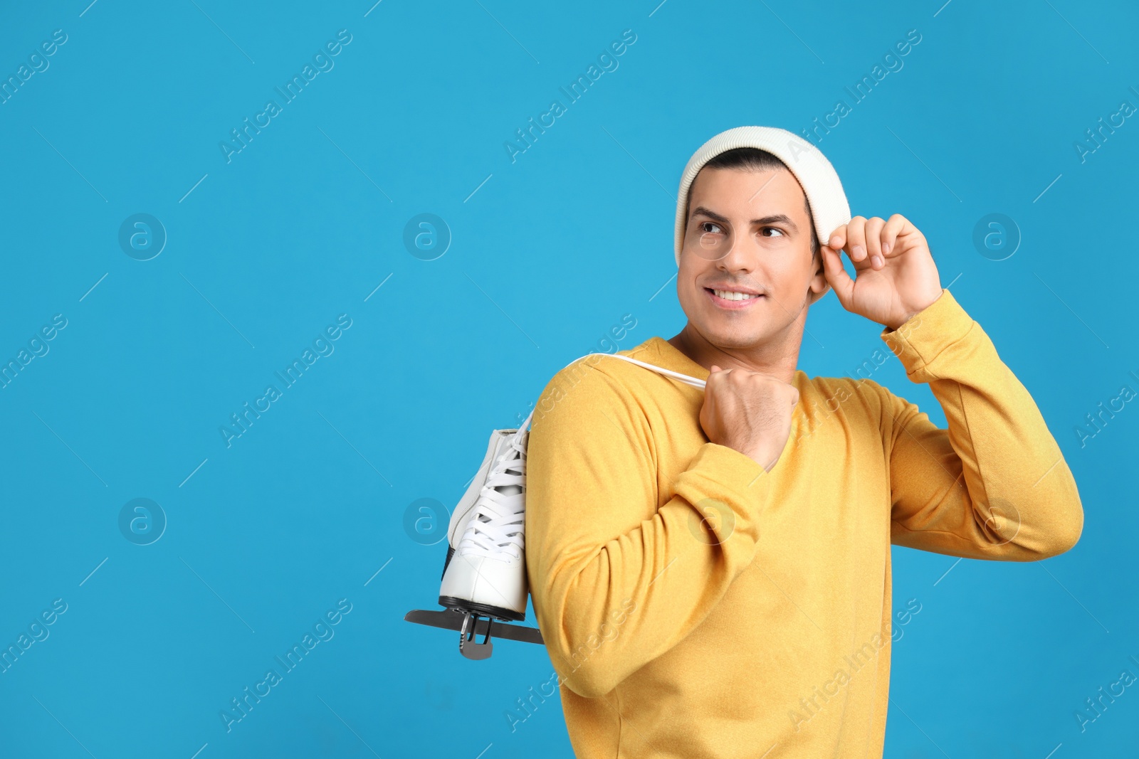 Happy man with ice skates on light blue background. Space for text Photo of Happy man with ice skates on light blue background. Space for text