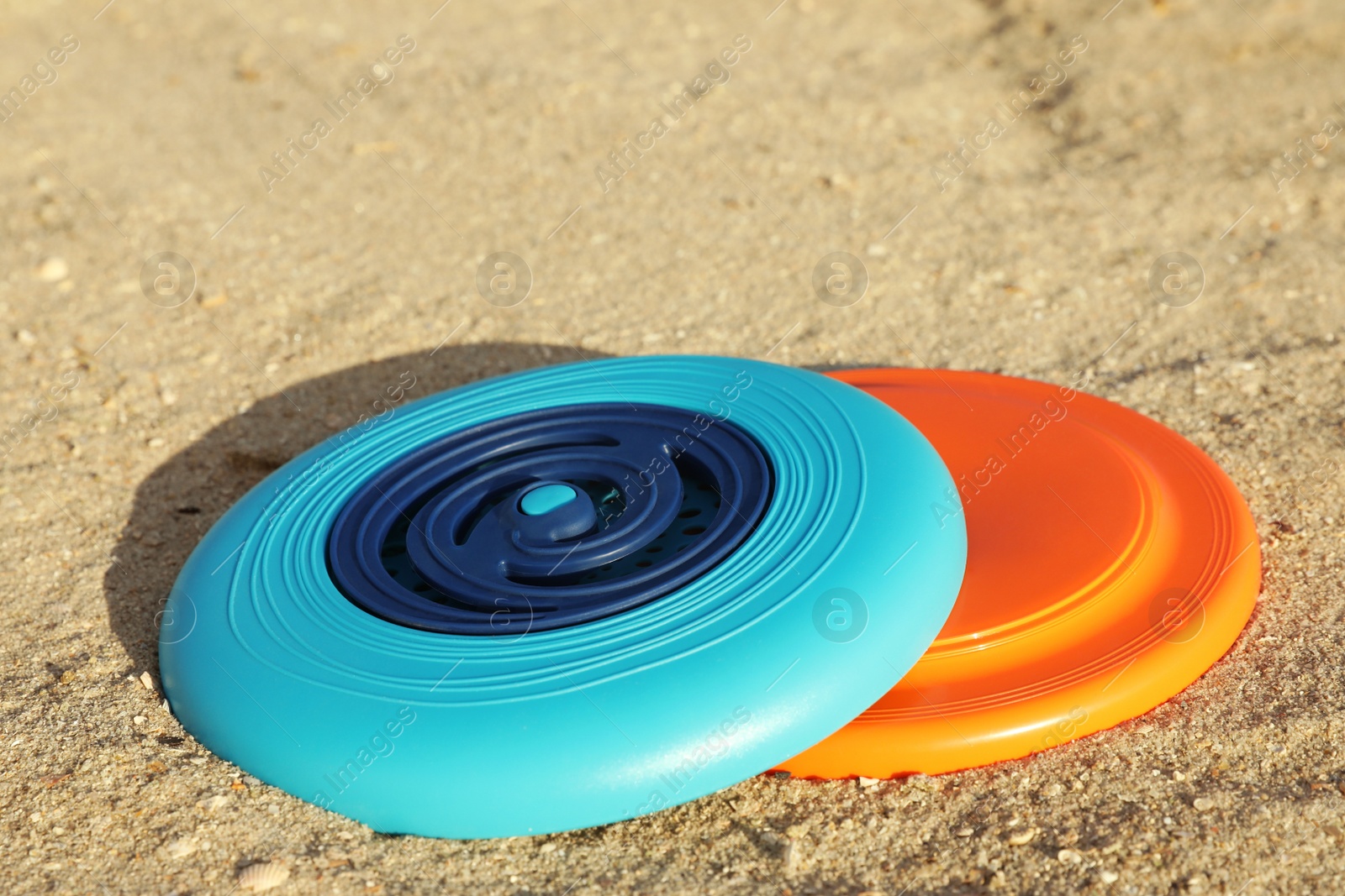New plastic frisbee discs on sandy beach Photo of New plastic frisbee discs on sandy beach