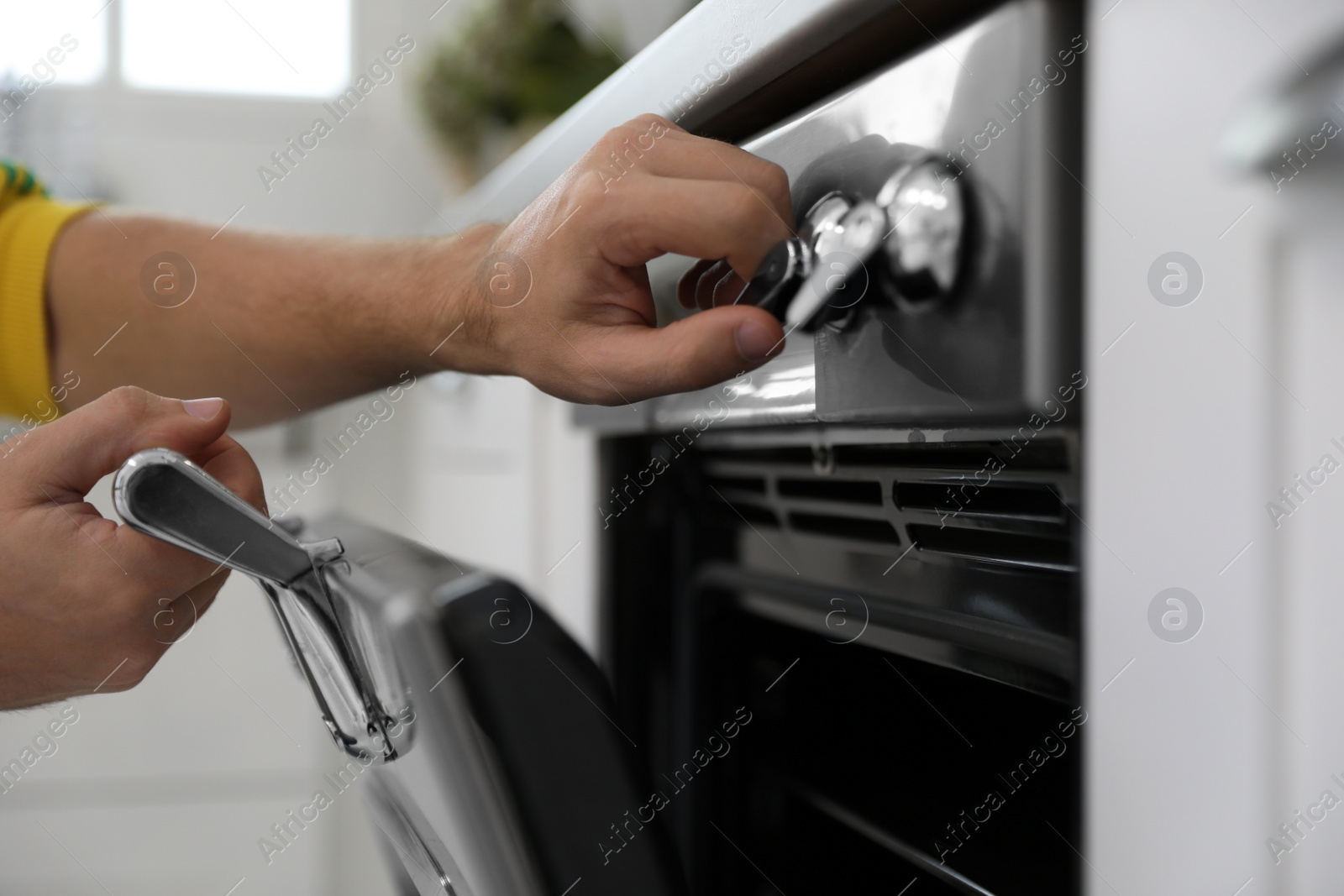 Man using modern oven in kitchen, closeup Photo of Man using modern oven in kitchen, closeup