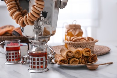 Traditional Russian samovar with treats on white table at home Photo of Traditional Russian samovar with treats on white table at home