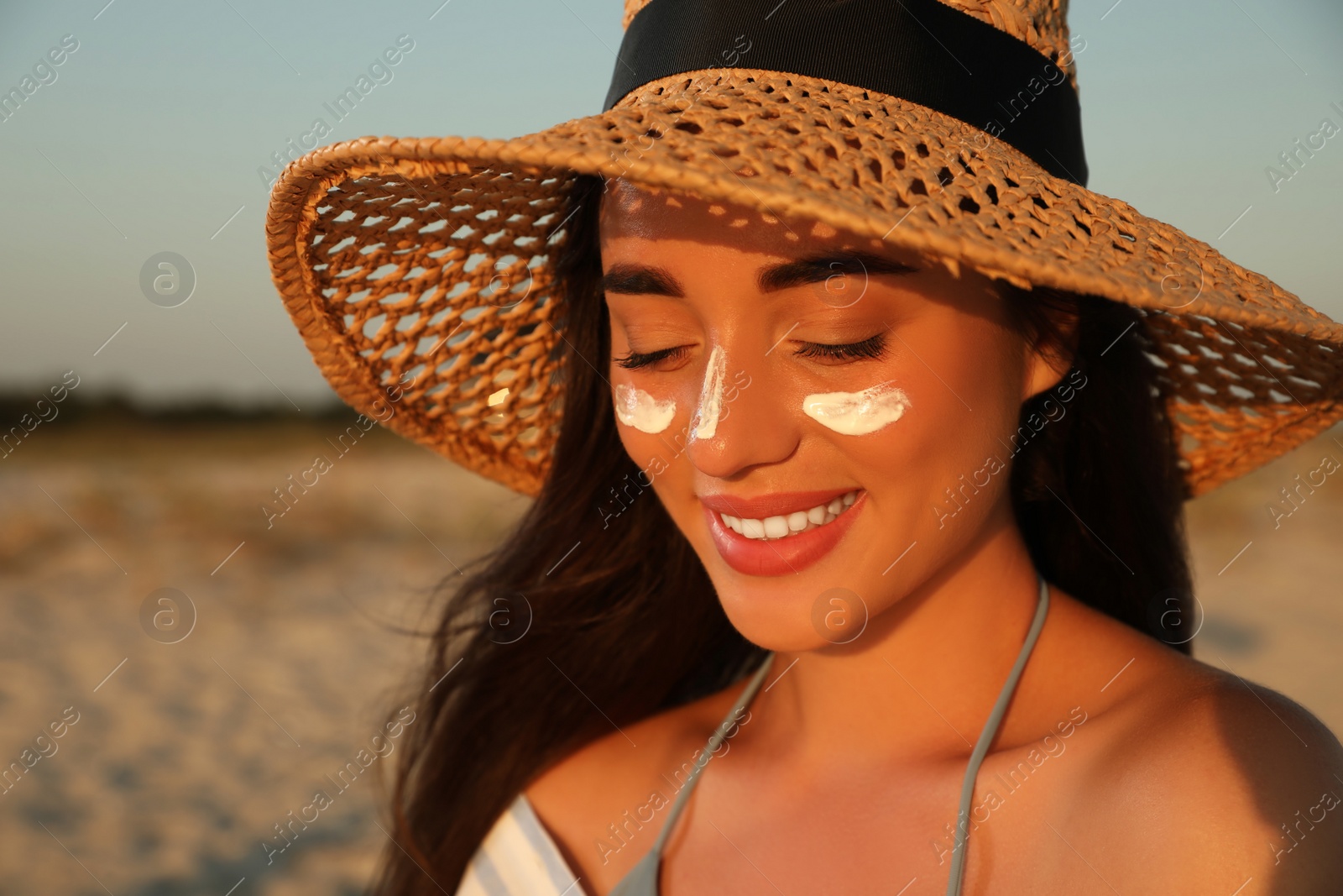 Happy young woman with sun protection cream on face at beach Photo of Happy young woman with sun protection cream on face at beach