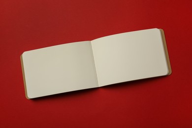 Stylish open notebook with blank sheets on red background, top view Photo of Stylish open notebook with blank sheets on red background, top view