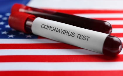 Test tubes with blood samples on American flag, closeup. Coronavirus pandemic in USA Photo of Test tubes with blood samples on American flag, closeup. Coronavirus pandemic in USA