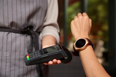 Woman making payment with smart watch outdoors, closeup Photo of Woman making payment with smart watch outdoors, closeup