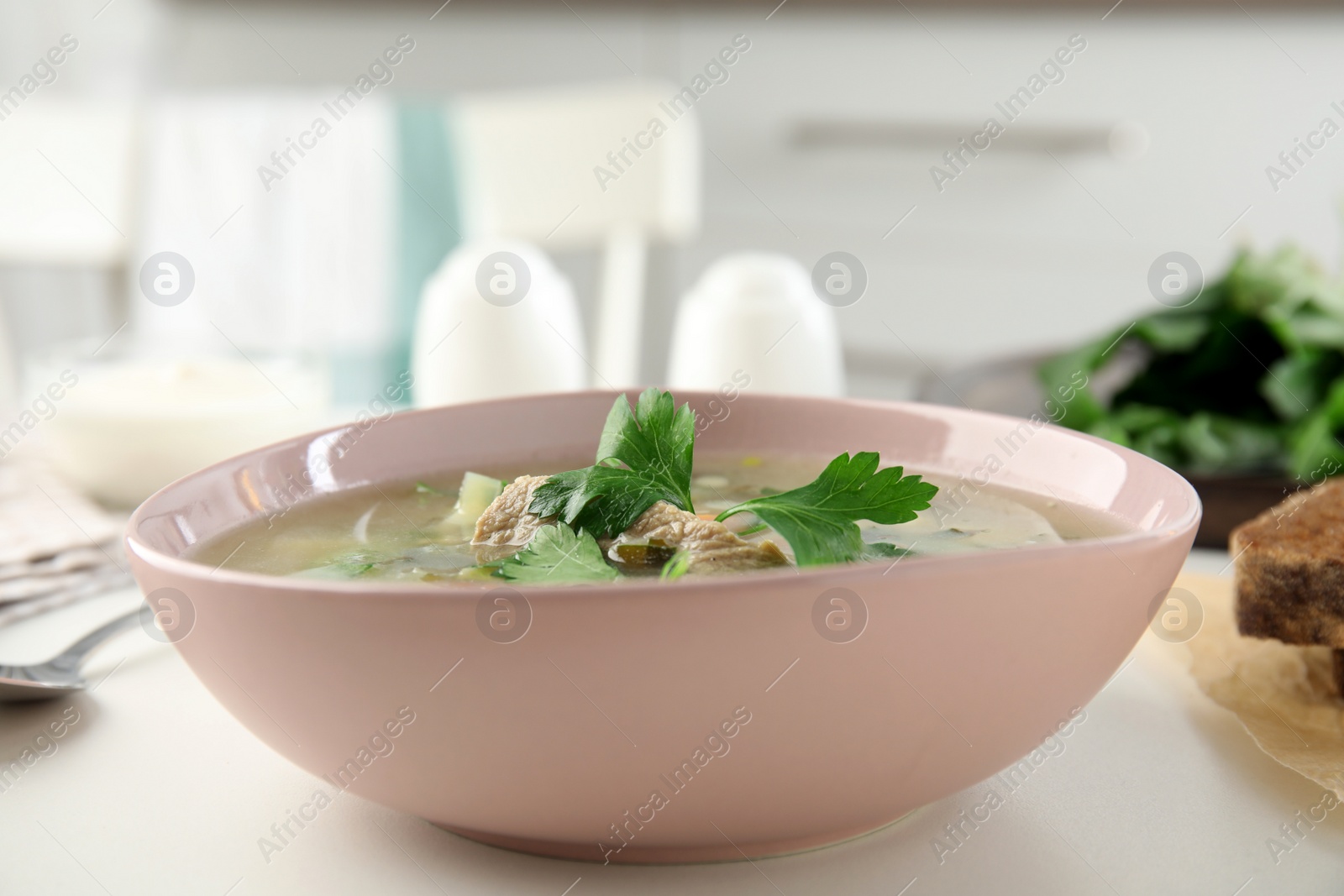Delicious sorrel soup with meat and parsley served on white table Photo of Delicious sorrel soup with meat and parsley served on white table
