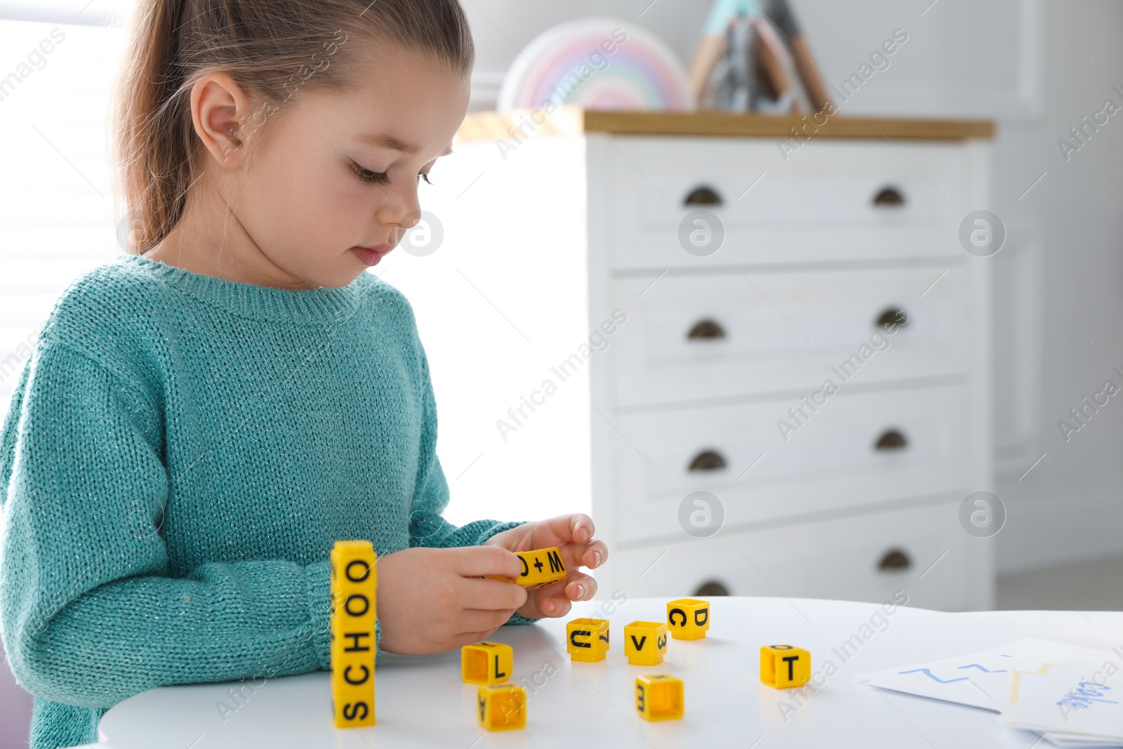 Little girl assembling word with yellow bricks in classroom at English lesson Photo of Little girl assembling word with yellow bricks in classroom at English lesson