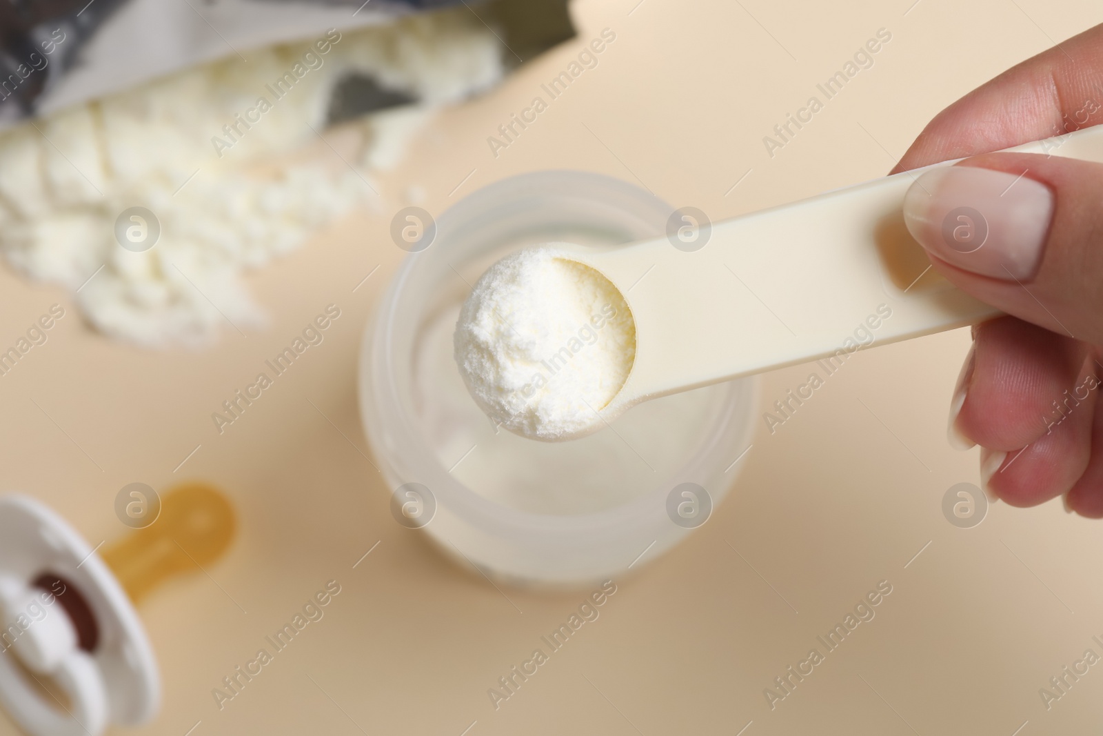 Woman preparing infant formula on beige background, top view. Baby milk Photo of Woman preparing infant formula on beige background, top view. Baby milk