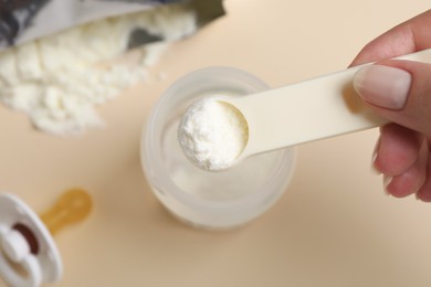 Woman preparing infant formula on beige background, top view. Baby milk Photo of Woman preparing infant formula on beige background, top view. Baby milk