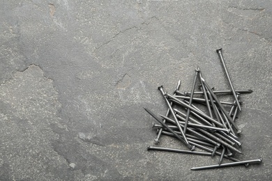 Pile of metal nails on grey stone background, flat lay. Space for text Photo of Pile of metal nails on grey stone background, flat lay. Space for text