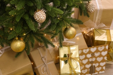 Photo of Pile of gift boxes near Christmas tree with fairy lights