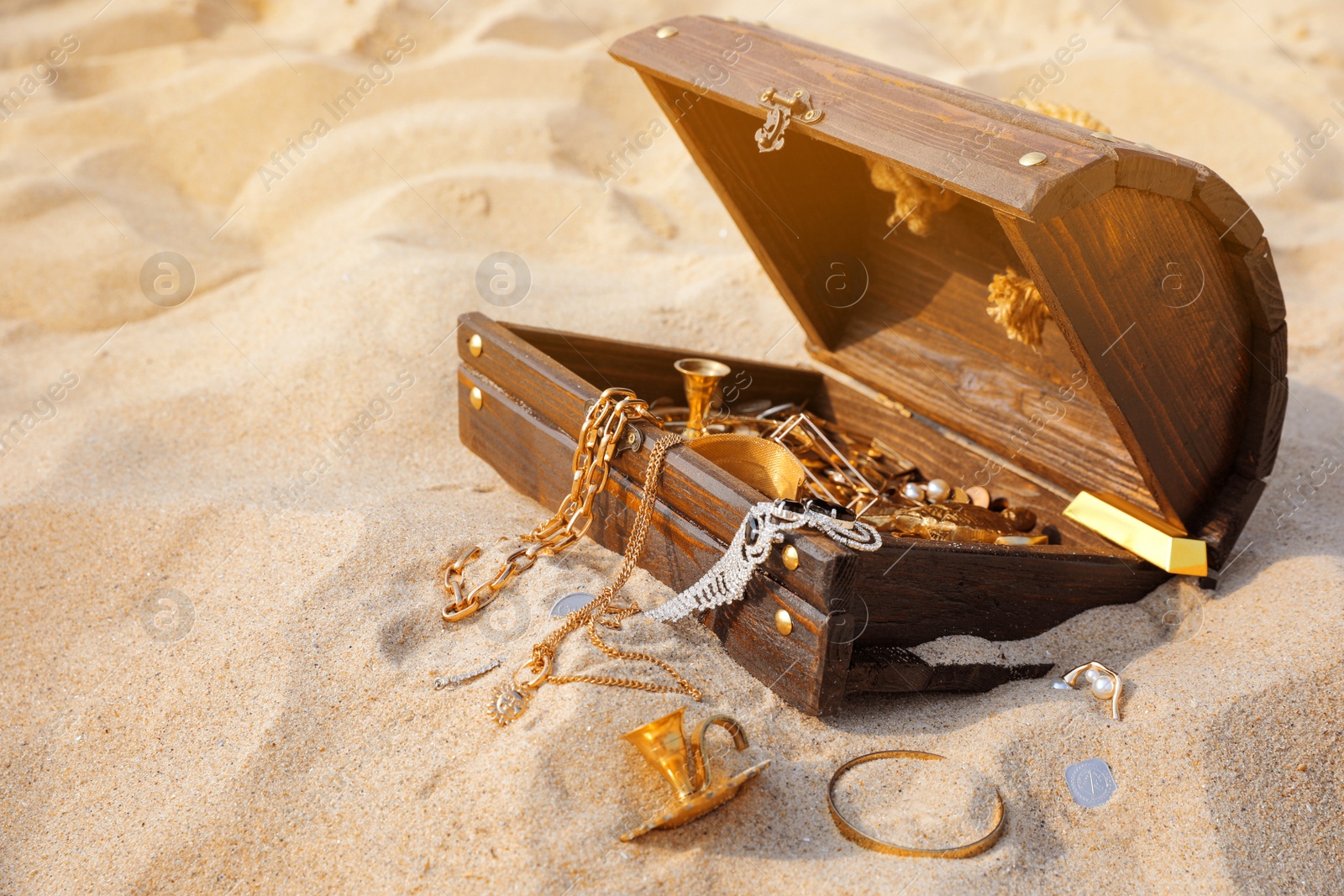 Open wooden treasure chest on sand, space for text Photo of Open wooden treasure chest on sand, space for text
