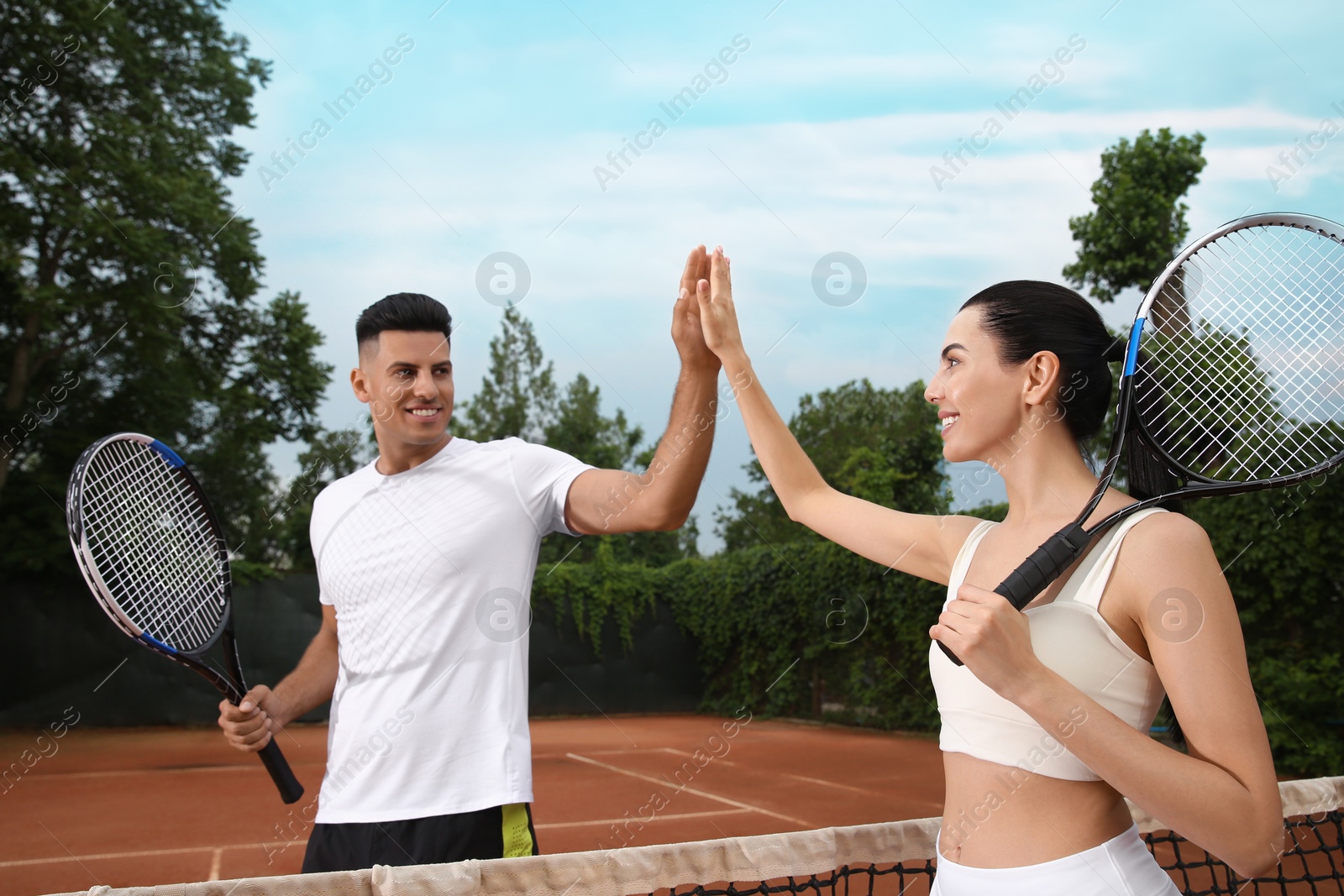Woman giving man high five at tennis court Photo of Woman giving man high five at tennis court