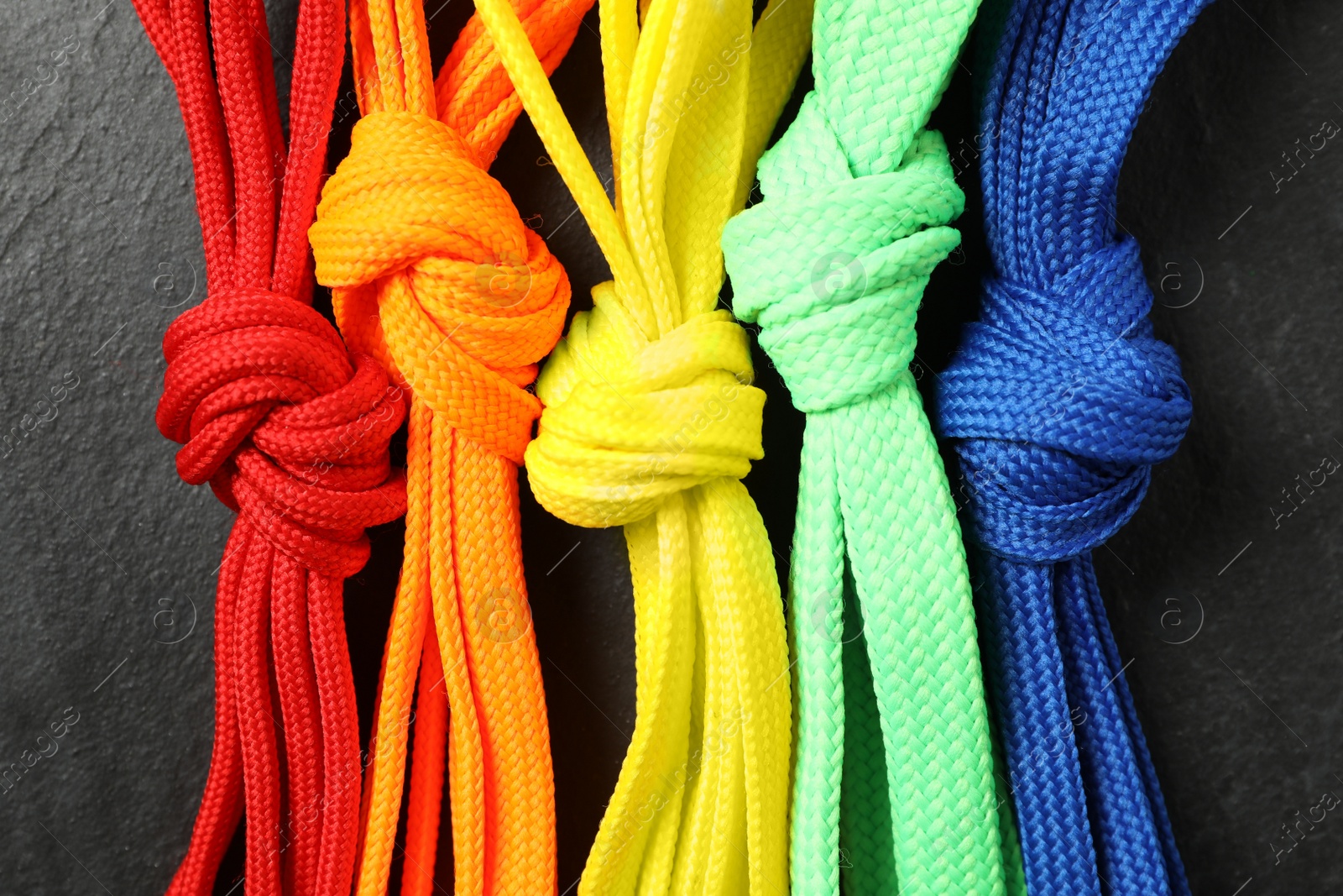 Colorful shoelaces on black background, flat lay Photo of Colorful shoelaces on black background, flat lay