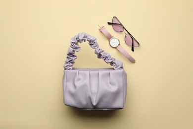 Photo of Stylish woman's bag, watch and sunglasses on beige background, flat lay