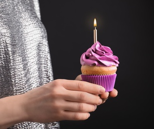 Woman holding birthday cupcake on black background Photo of Woman holding birthday cupcake on black background