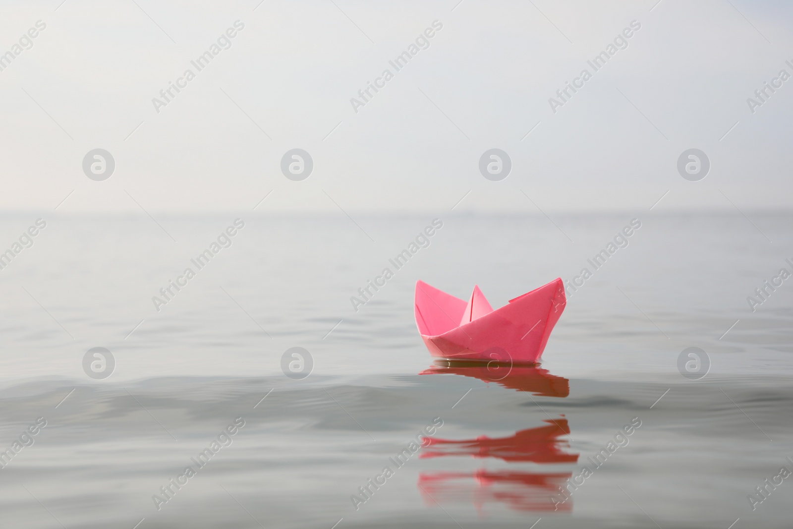 Pink paper boat on water surface, space for text Photo of Pink paper boat on water surface, space for text