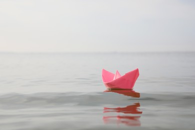 Pink paper boat on water surface, space for text Photo of Pink paper boat on water surface, space for text