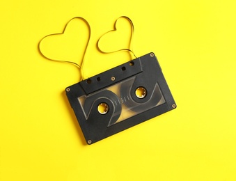 Music cassette and hearts made with tape on yellow background, top view. Listening love song Photo of Music cassette and hearts made with tape on yellow background, top view. Listening love song