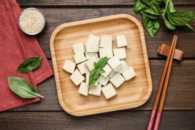 Delicious tofu with basil served on wooden table, flat lay Photo of Delicious tofu with basil served on wooden table, flat lay