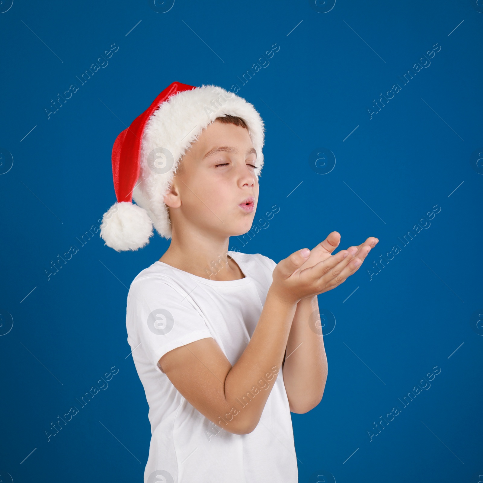 Happy little child in Santa hat on blue background. Christmas celebration Image of Happy little child in Santa hat on blue background. Christmas celebration