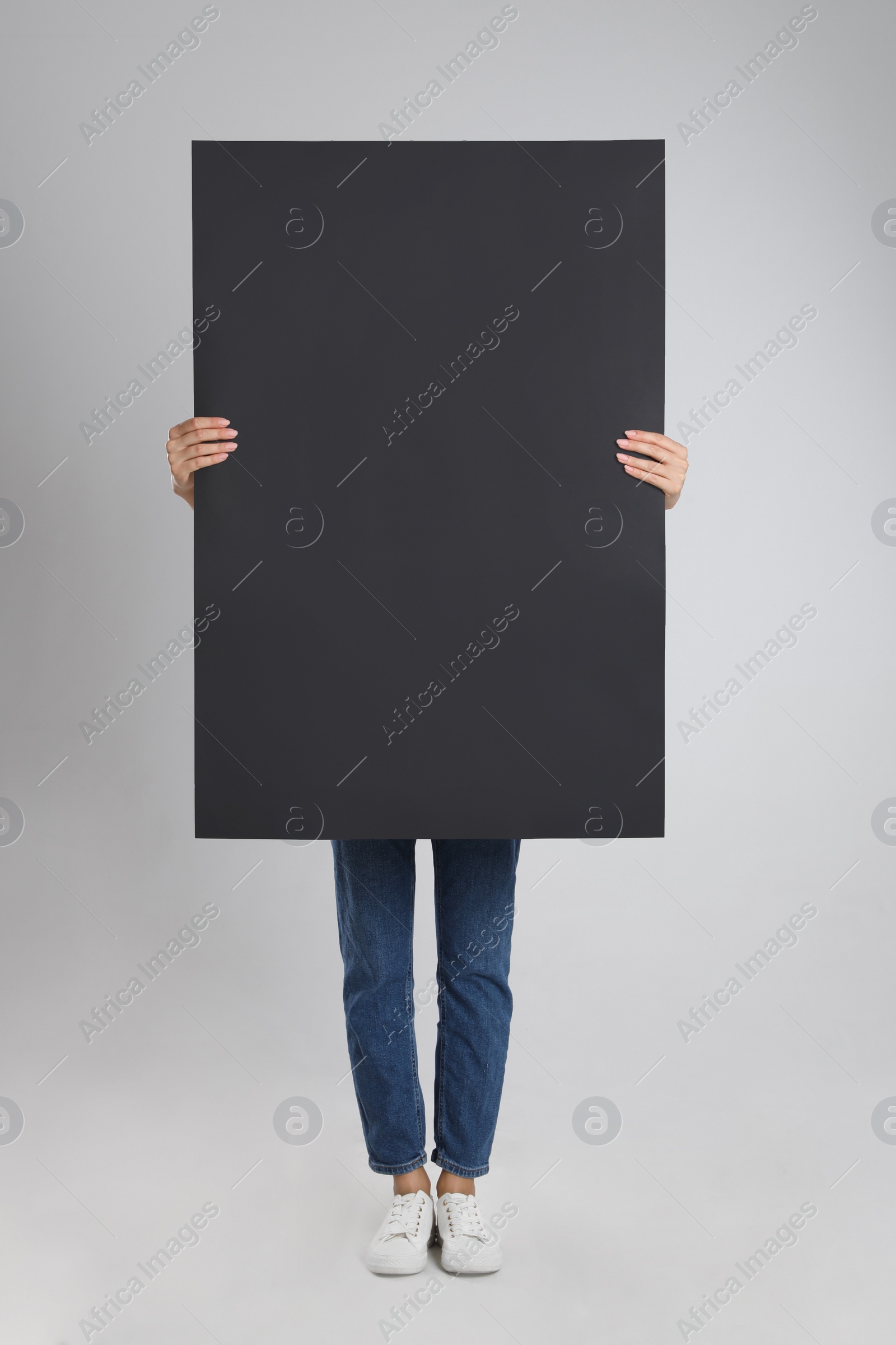 Woman holding blank poster on light grey background Photo of Woman holding blank poster on light grey background