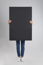 Woman holding blank poster on light grey background Photo of Woman holding blank poster on light grey background