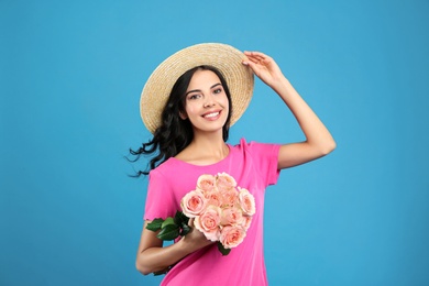Portrait of smiling woman with beautiful bouquet on light blue background Photo of Portrait of smiling woman with beautiful bouquet on light blue background