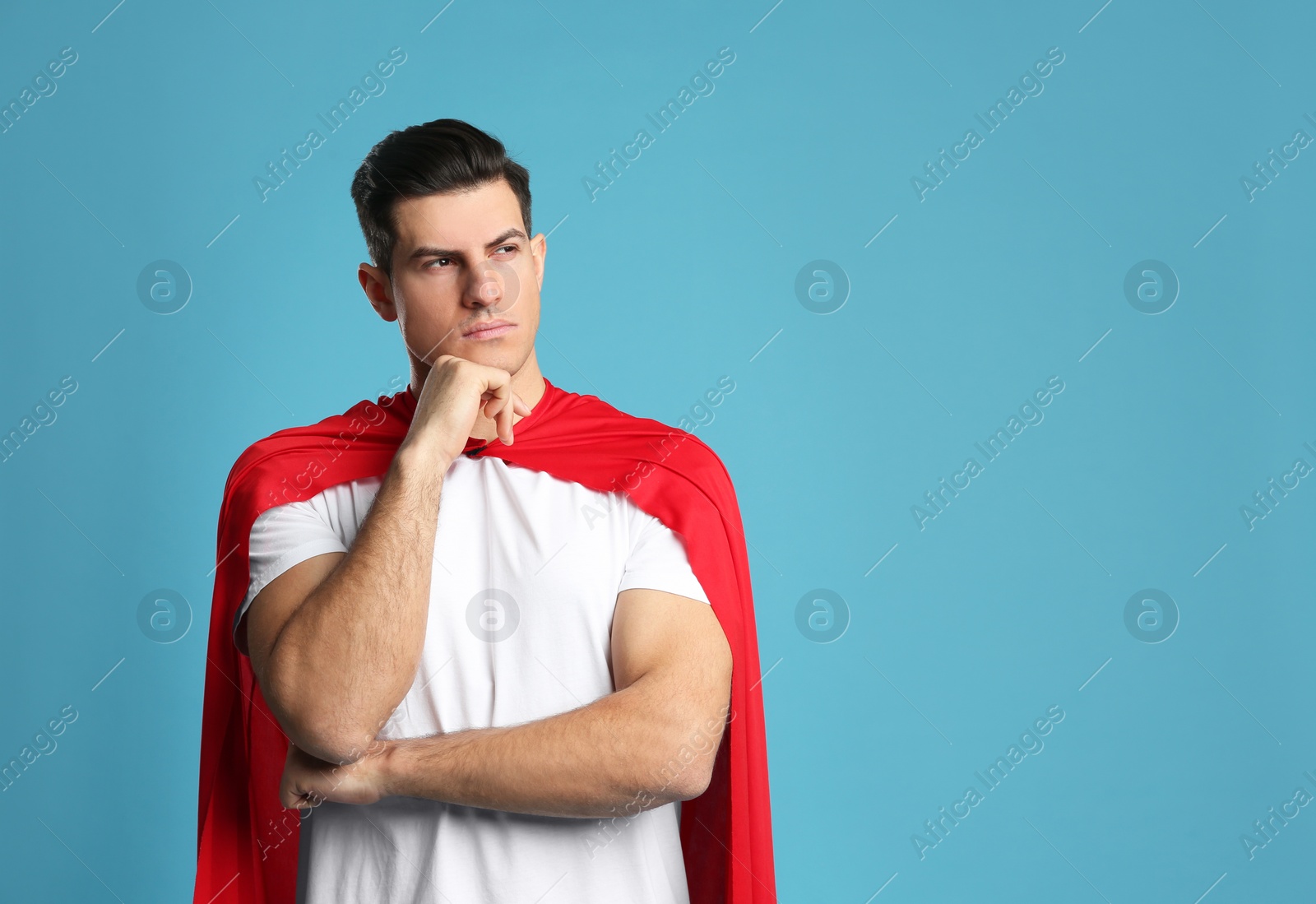 Man wearing superhero cape on light blue background. Space for text Photo of Man wearing superhero cape on light blue background. Space for text