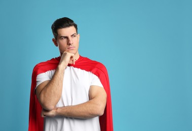 Man wearing superhero cape on light blue background. Space for text Photo of Man wearing superhero cape on light blue background. Space for text