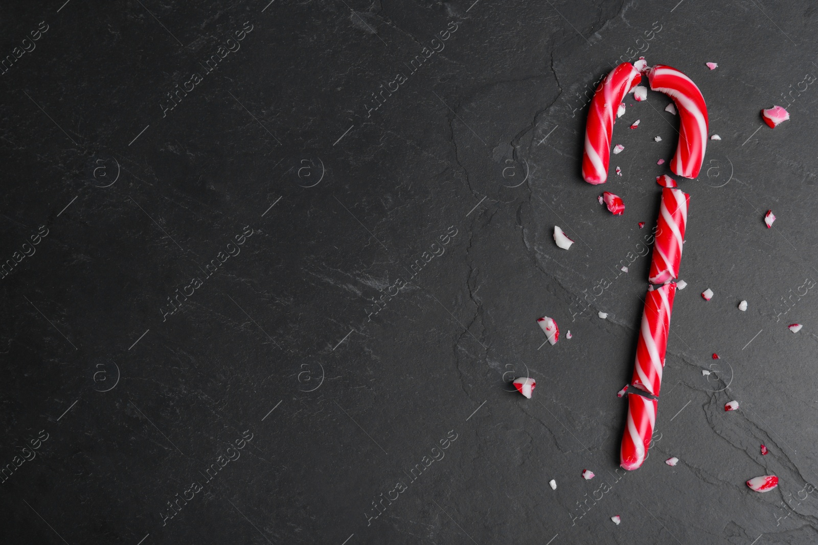 Crushed Christmas candy cane on black background, flat lay. Space for text Photo of Crushed Christmas candy cane on black background, flat lay. Space for text