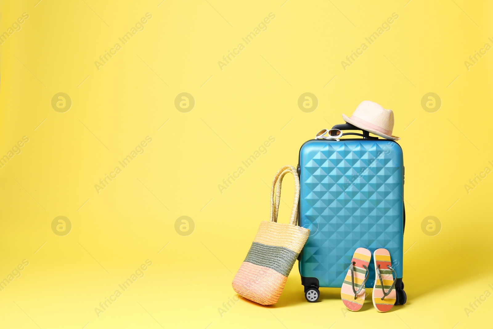 Blue suitcase with beach accessories on yellow background. Space for text Photo of Blue suitcase with beach accessories on yellow background. Space for text