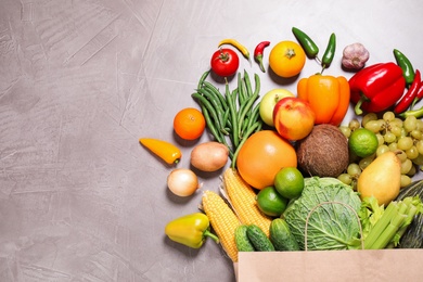 Paper bag with assortment of fresh organic fruits and vegetables on grey table, flat lay. Space for text Photo of Paper bag with assortment of fresh organic fruits and vegetables on grey table, flat lay. Space for text