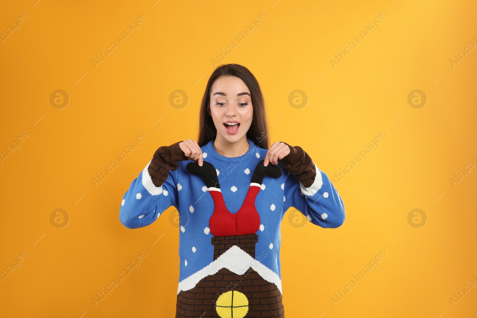 Young woman in Christmas sweater on yellow background Photo of Young woman in Christmas sweater on yellow background