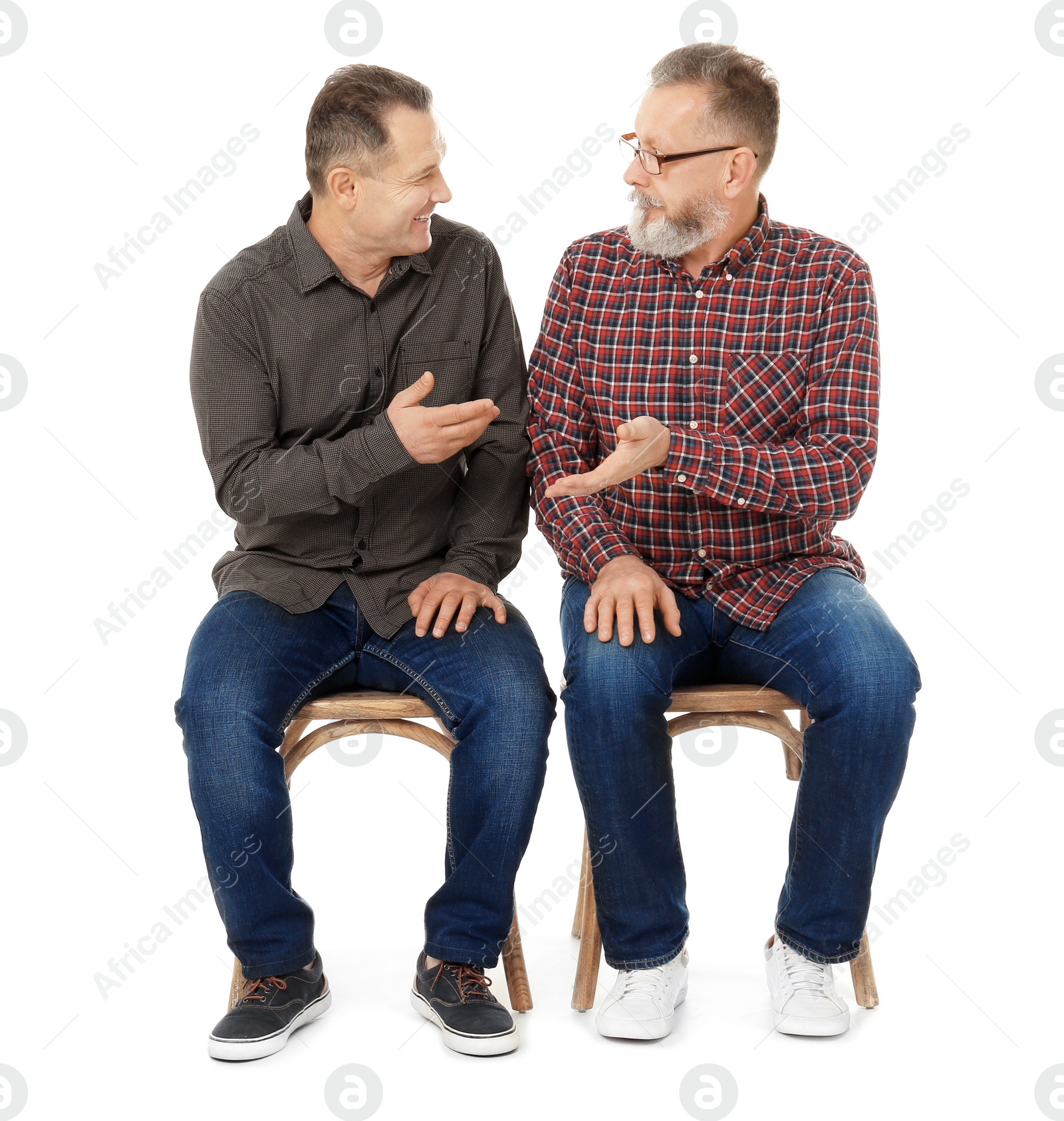 Happy senior men sitting on chairs against white background Photo of Happy senior men sitting on chairs against white background