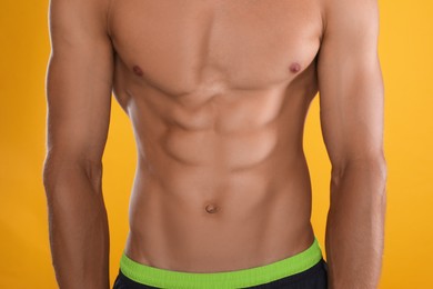 Shirtless man with slim body on yellow background, closeup Photo of Shirtless man with slim body on yellow background, closeup