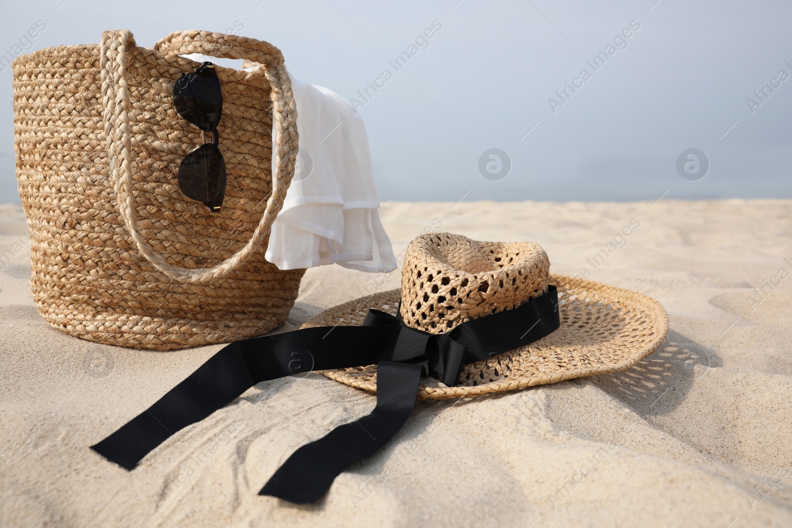 Beach bag, towel, sunglasses and hat on sandy seashore, space for text Photo of Beach bag, towel, sunglasses and hat on sandy seashore, space for text