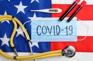 Test tubes with blood samples, medical mask and stethoscope on American flag, flat lay. Coronavirus pandemic in USA Photo of Test tubes with blood samples, medical mask and stethoscope on American flag, flat lay. Coronavirus pandemic in USA