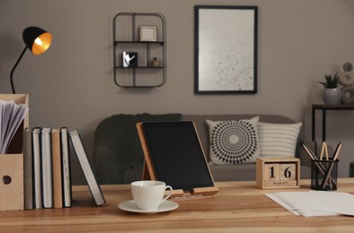 Comfortable workplace with tablet on wooden table in modern office. Interior design Photo of Comfortable workplace with tablet on wooden table in modern office. Interior design