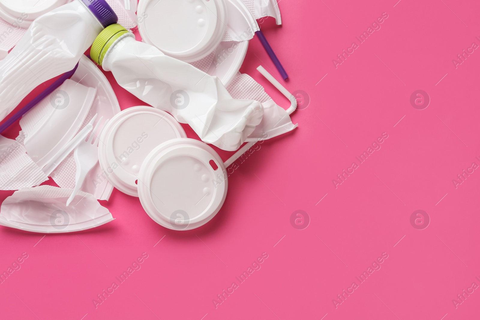 Pile of different plastic items on pink background, flat lay. Space for text Photo of Pile of different plastic items on pink background, flat lay. Space for text