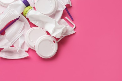 Pile of different plastic items on pink background, flat lay. Space for text Photo of Pile of different plastic items on pink background, flat lay. Space for text