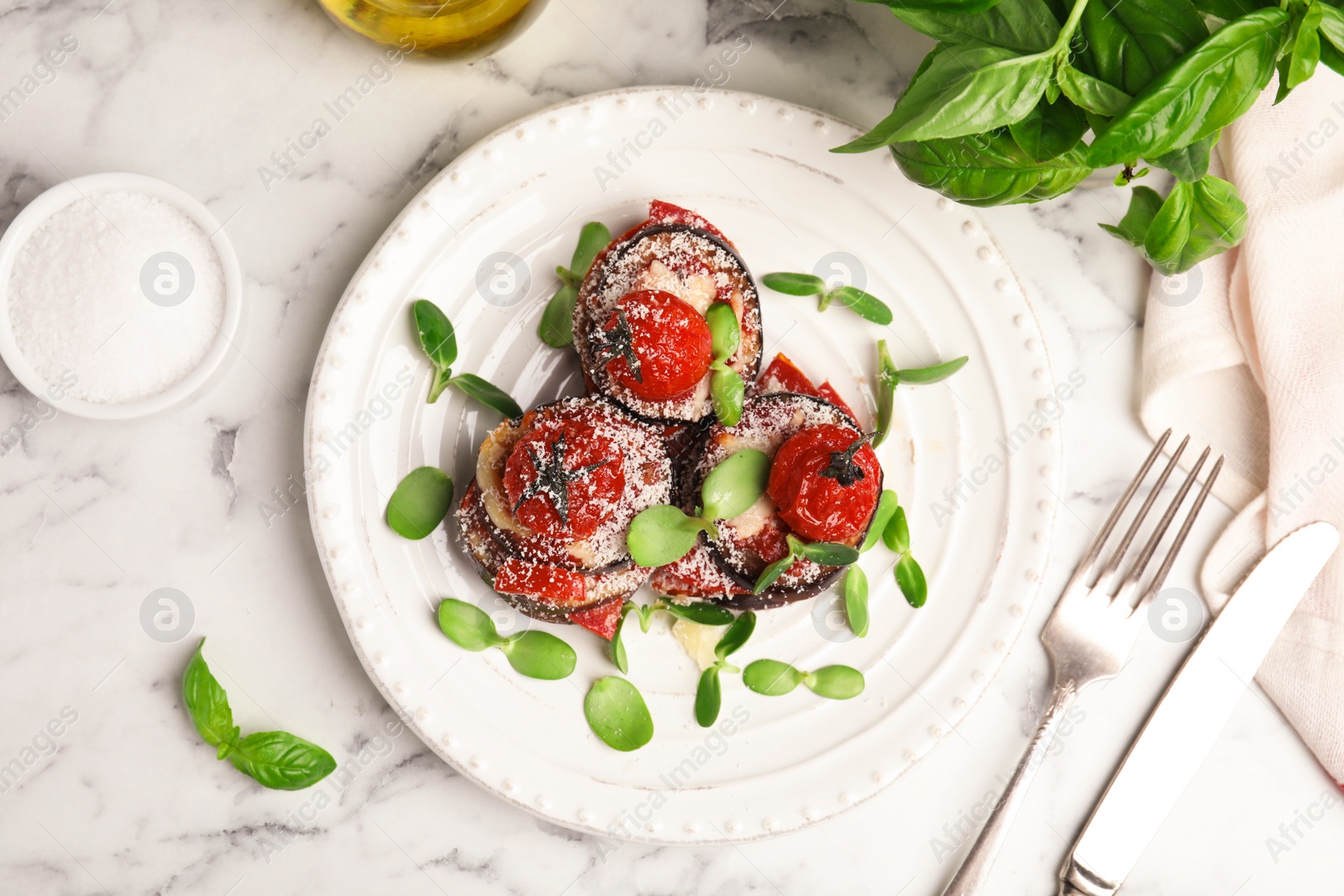 Baked eggplant with tomatoes, cheese and basil served on white marble table, flat lay Photo of Baked eggplant with tomatoes, cheese and basil served on white marble table, flat lay