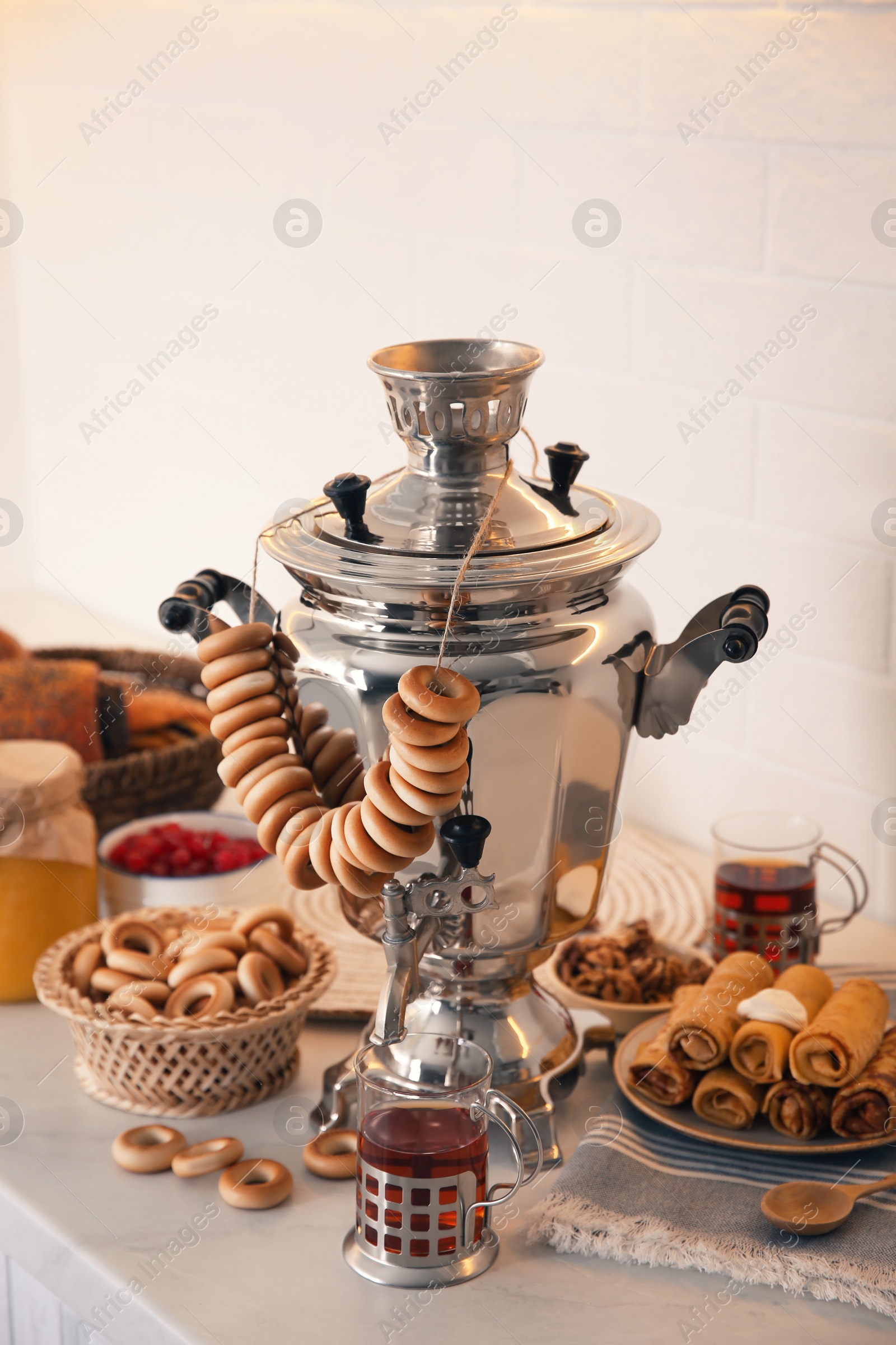 Traditional Russian samovar with treats on white table Photo of Traditional Russian samovar with treats on white table
