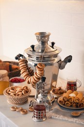 Traditional Russian samovar with treats on white table Photo of Traditional Russian samovar with treats on white table