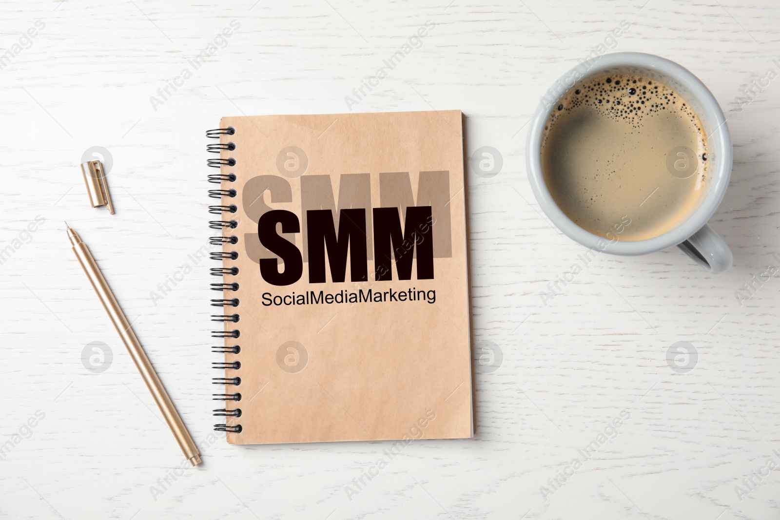 Notebook with text SMM (Social media marketing, cup of coffee and pen on white wooden background, flat lay Image of Notebook with text SMM (Social media marketing, cup of coffee and pen on white wooden background, flat lay