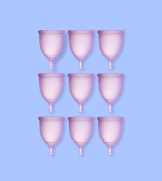 Image of Many purple menstrual cups on light blue background, flat lay 