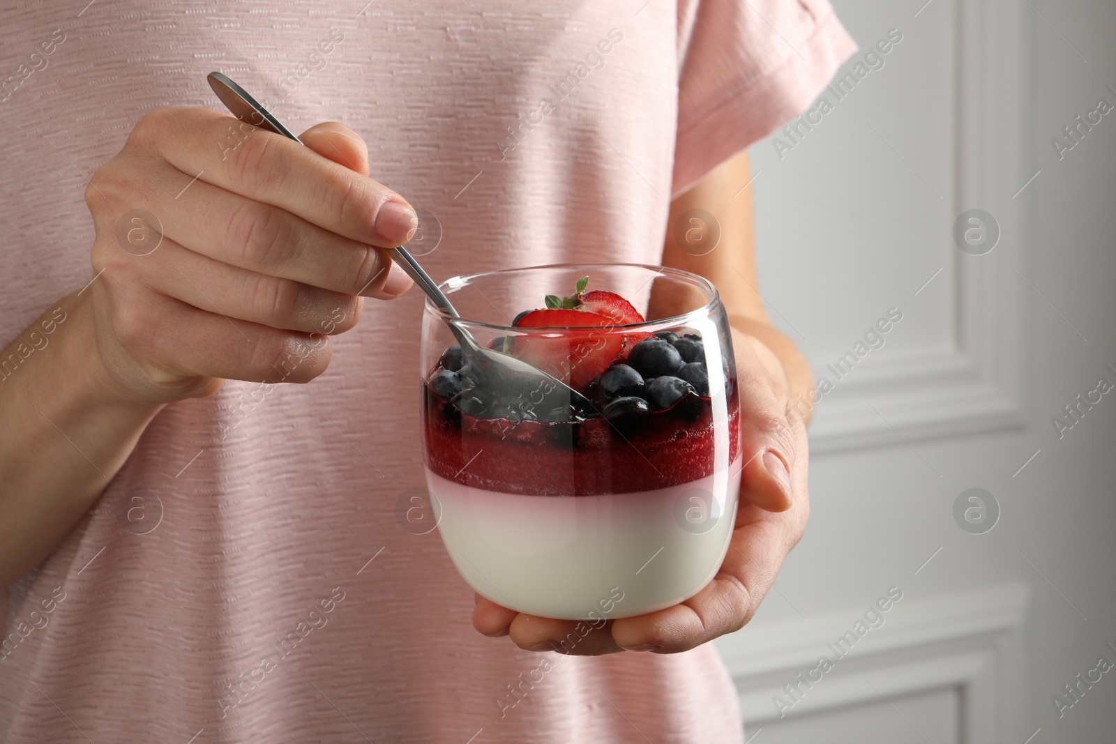 Woman eating delicious panna cotta with berries, closeup Photo of Woman eating delicious panna cotta with berries, closeup