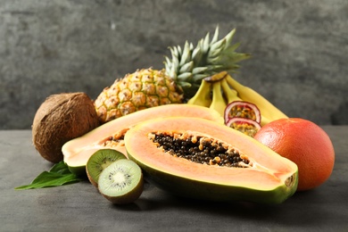 Photo of Fresh ripe papaya and other fruits on grey table