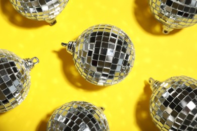 Shiny disco balls on yellow background, flat lay Photo of Shiny disco balls on yellow background, flat lay