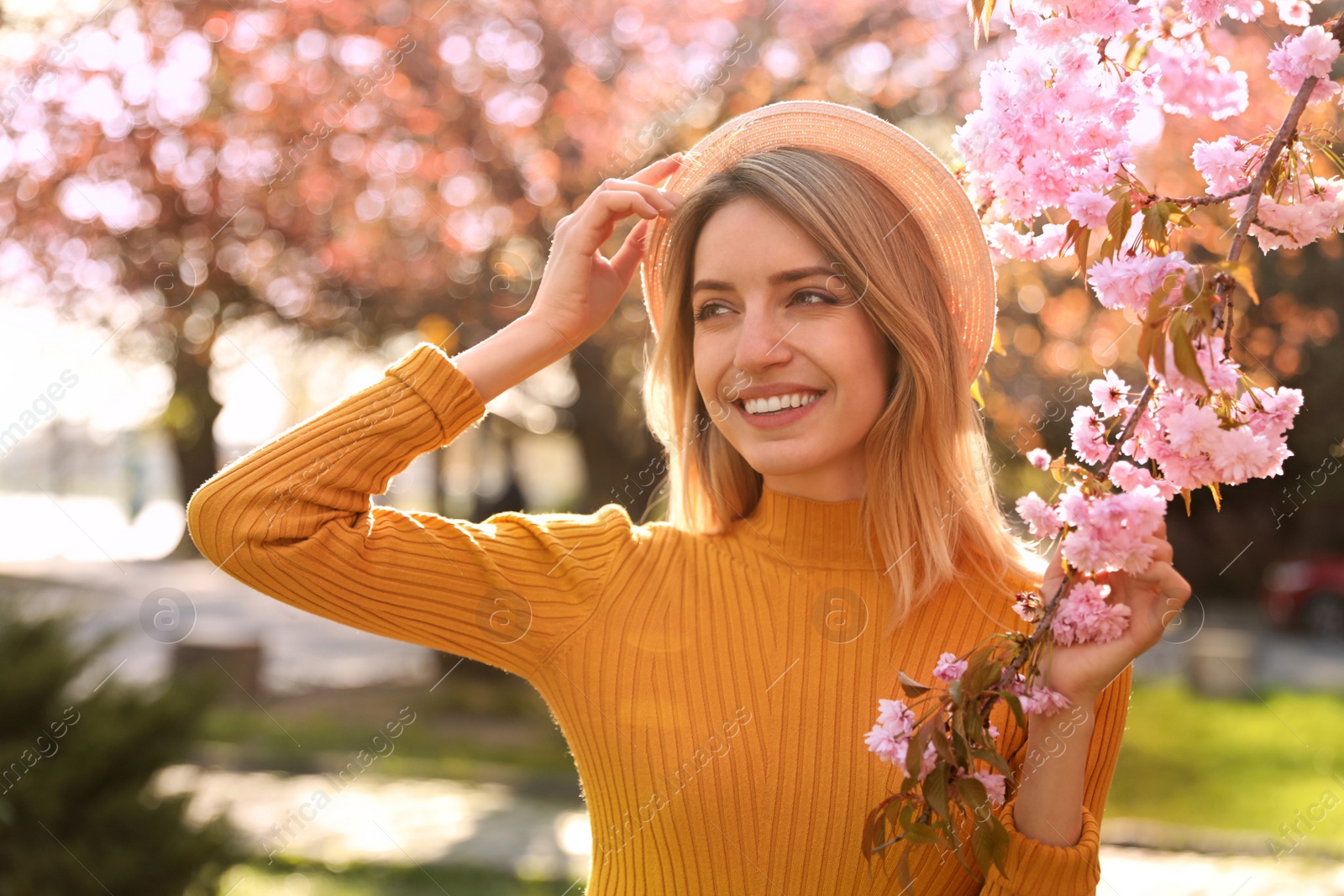 Young woman wearing stylish outfit near blossoming sakura in park. Fashionable spring look Photo of Young woman wearing stylish outfit near blossoming sakura in park. Fashionable spring look