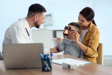 Mother and son visiting pediatrician in hospital. Doctor playing with little boy Photo of Mother and son visiting pediatrician in hospital. Doctor playing with little boy